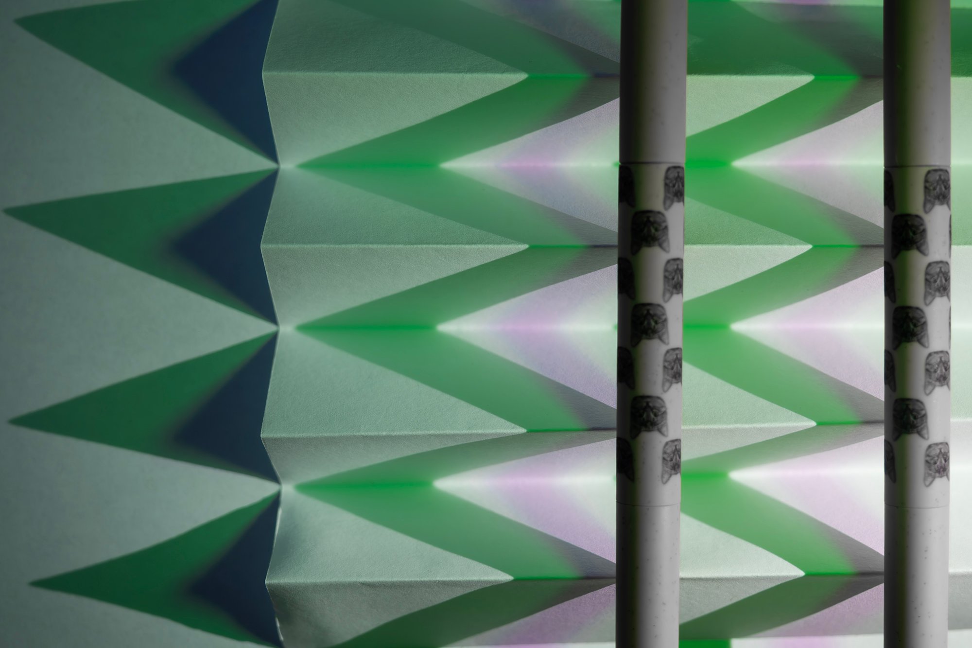 Repeated folded triangular planes lit in green and violet, intersected by two vertical cylindrical forms.