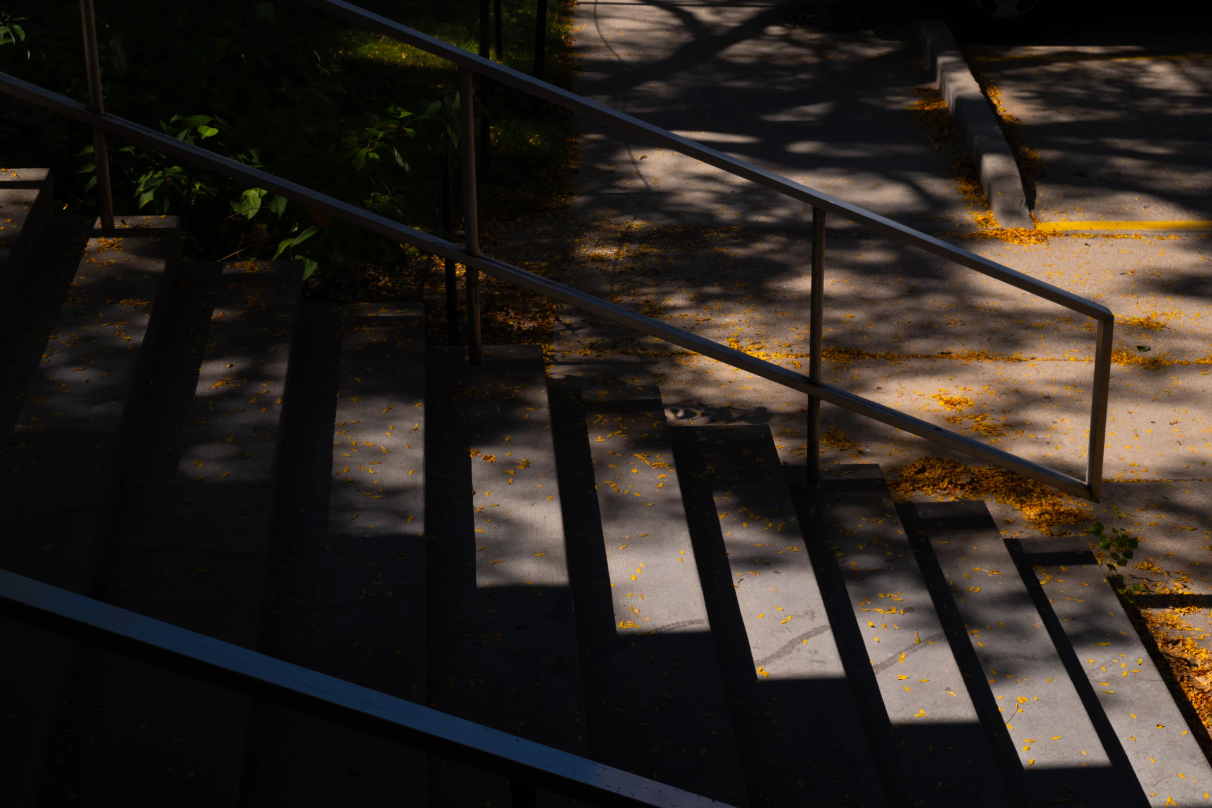 Angular shadows crossing an outdoor stairway and handrail.